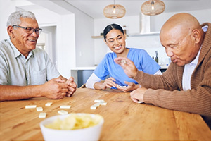 PACS-300x200-activity2 two elderly gentlemen and a caregiver playing games at a table