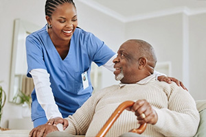 PACS-300x200-caregiver2 an African American nurse helping an elderly gentleman who's holding his cane